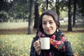 Girl in an autumn part with a white cup of hot drink Royalty Free Stock Photo