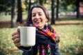 Girl in an autumn part with a white cup of hot drink