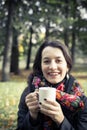 Girl in an autumn part with a white cup of hot drink Royalty Free Stock Photo