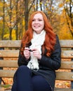 Girl in autumn season listen music on audio player with headphones, sit on bench in city park, yellow trees and fallen leaves Royalty Free Stock Photo