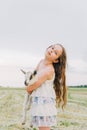 Girl with baby goat on farm outdoors. Love and care. Village animals. happy child hugs goat, concept of unity of nature Royalty Free Stock Photo