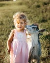 Girl with baby goat on farm outdoors. Love and care. Village animals. happy child hugs goat, concept of unity of nature Royalty Free Stock Photo