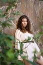 girl on a background of a brick wall with tree leaves. a combination of nature and construction. alive and not alive.