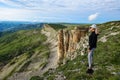 A girl on the background of two monks rocks in a cloud, Bermamyt plateau, Karachay-Cherkess Republic