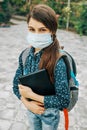 Girl With A Backpack Behind Her Back Goes To School. There Is A Medical Mask On Her Face