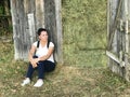 A girl with a backpack behind her. Sits by a wooden shed that is filled with hay Royalty Free Stock Photo