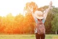 Girl with backpack and hat stands back with hands up against the forest. Toning