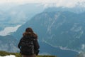 A girl with backpack looking beautiful aerial view of mountain and Hallstatt city in Austria in summer