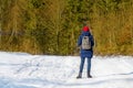 Girl with a backpack in red hat standing in a snowy forest. Winter sunny day