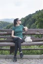 Girl with a backpack sitting on the bench. Forest on background Royalty Free Stock Photo