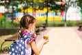 Girl with a backpack take off the medical mask and eating pie near the school. A quick snack with a bun, unhealthy food, lunch Royalty Free Stock Photo