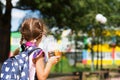 Girl with a backpack take off the medical mask and eating pie near the school. A quick snack with a bun, unhealthy food, lunch