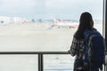 Girl with backpack traveling watching aircraft in the airport.