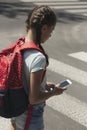 Girl using smartphone while walking through crosswalk to the school Royalty Free Stock Photo