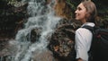 Girl backpacker look at jungle cascade waterfall