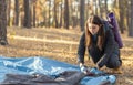 Girl backpacker setting up tent, forest background