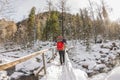 Girl backpacker walking on a bridge over a frozen river in the w Royalty Free Stock Photo