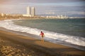 Girl with a bag walking on the beach on sunny day. Stylish hipster near the waves on the sea. Holiday travel concept. Barcelona