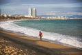 Girl with a bag walking on the beach on sunny day. Stylish hipster near the waves on the sea. Holiday travel concept. Barcelona