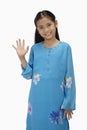 Girl in baju kurung smiling and waving at the camera. Conceptual image