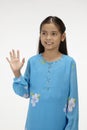 Girl in baju kurung smiling and waving. Conceptual image