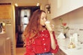 The girl in the bakery eats dessert. Beautiful model in a cafe eats sweets and smiling. Beautiful girl in a red sweater Royalty Free Stock Photo