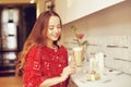 The girl in the bakery eats dessert. Beautiful model in a cafe eats sweets and smiling. Beautiful girl in a red sweater Royalty Free Stock Photo