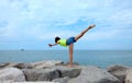 girl balancing on one leg while doing gymnastics on the rocks by the sea Royalty Free Stock Photo