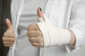 A girl with a bandaged hand shows a thumbs up, a hand injury, an elastic bandage, first aid to the patient Royalty Free Stock Photo