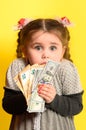 Girl with banknotes in hands on a yellow background, business child with world currency.