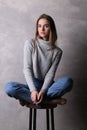 Girl on a bar chair with crossed legs. Gray background Royalty Free Stock Photo