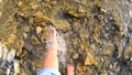 Girl bare foot water sprays on stones of shallow river close-up, sunny summer