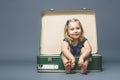 Girl barefoot sitting inside an old suitcase