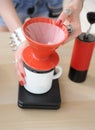 Girl barista brewing drip coffee in red pour over v60 hario close up without face. Manual grinder