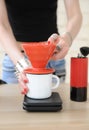 Girl barista brewing drip coffee in red pour over v60 hario close up without face. Manual grinder