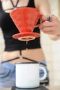 Girl barista brews coffee in red v60 pourover. Dripping water from funnel in hand into white cup on electronic scale Royalty Free Stock Photo