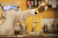 Girl bartender pours wine into a wine glass