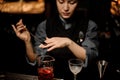 Girl bartender takes a spoon from a cocktail in the measuring glass cup