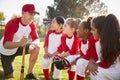Girl baseball team kneeling in a huddle with their coach Royalty Free Stock Photo