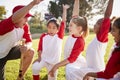 Girl baseball team kneeling with their coach, raising hands Royalty Free Stock Photo