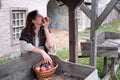 A girl with a basket of apples stands at the counter of the medieval market Royalty Free Stock Photo