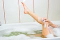 Girl in the bath with foam washes leg