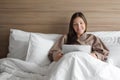 Girl in bathrobe studies online with tablet in hotel bed