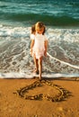 Girl at the beach drawing heart on a sand Royalty Free Stock Photo