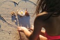 Girl at beach drawing heart on sand Royalty Free Stock Photo