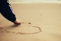 Girl at the beach drawing hearts on a sand.