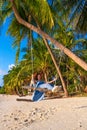 The girl on the beach rides on a swing during sunset. Sunset in the tropics, enjoying nature. Swing tied to a palm tree by the Royalty Free Stock Photo