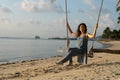 The girl on the beach rides on a swing during sunset. Sunset in the tropics, enjoying nature. Swing tied to a palm tree by the Royalty Free Stock Photo