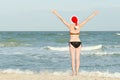 Girl on the beach in Santa hats. Hands raised up. Back view