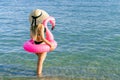 Girl by beach. Young sexy woman in straw hat, bikini swimsuit, sunglasses with pink inflatable flamingo in blue ocean water for Royalty Free Stock Photo